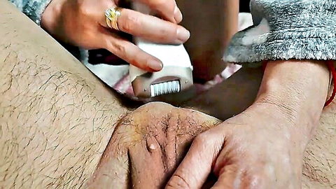 Wife trimming husband's hairy pubic mound with electric roller shaver closeup
