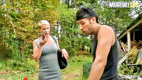 Blonde cougar Mia Wallace in gray dress outdoors with stud on phone
