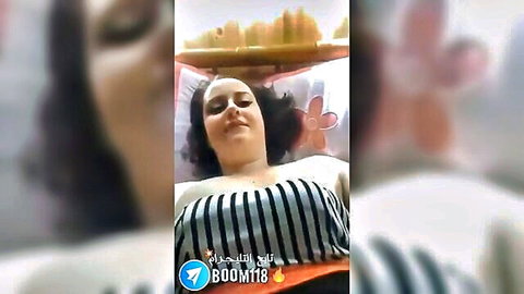 Arab woman lying relaxed on bed in striped top with deep cleavage