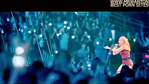 Taylor Swift performing on stage in sparkling red dress, mic in hand