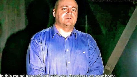 Bald white man in blue shirt standing in dim light, Painful Duel 9 trailer