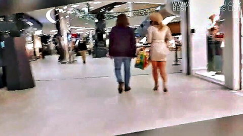 Blonde MILF big ass in tiny dress and stockings struts through mall store carrying bags