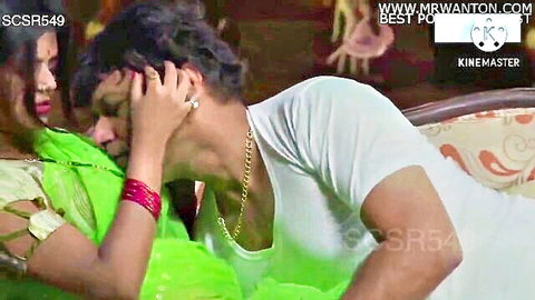 Indian woman in green saree passionately kissing muscular man on couch