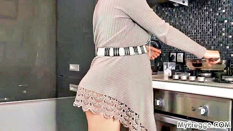 37-week pregnant woman in short lace dress bending over kitchen stove