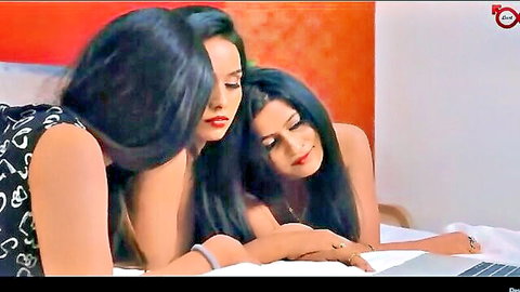 Two busty Indian women in tight tops leaning over laptop on bed