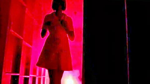 Brunette in tight red mini dress posing seductively in red-lit room