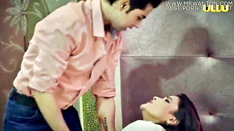 Indian couple in passionate kissing scene on bed, man in pink shirt leaning over woman