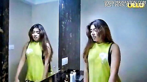 Indian woman in green tank top posing in bathroom mirror