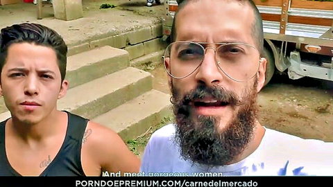 Bearded man with glasses talks excitedly to young tank-top guy outdoors near truck steps