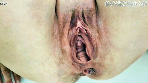 Close-up of mature hairy white woman's spread open pussy exposing pink wet vagina
