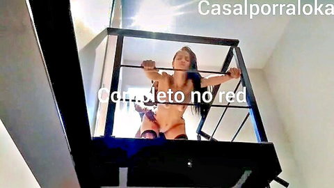 Bound nude Latina woman restrained in metal cage, explicit BDSM pose