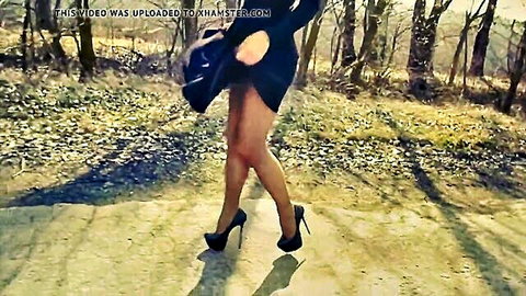 Sexy woman strutting in short black dress and high heels on outdoor path