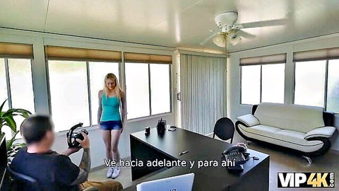 Blonde woman in teal tank top and short shorts stands before tattooed man with camera