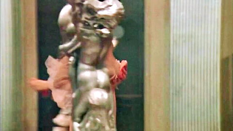 Debora Caprioglio in sheer dress embraces silver body-painted nude in Paprika 1991