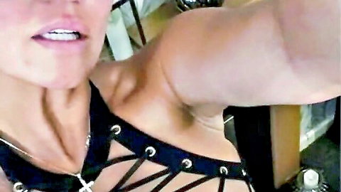 Sensual mature MILF in studded black harness top teasing with parted lips closeup selfie