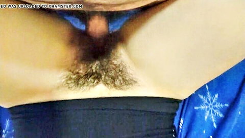 POV closeup of hairy erect cock with pink glans protruding from foreskin amid thick black pubes