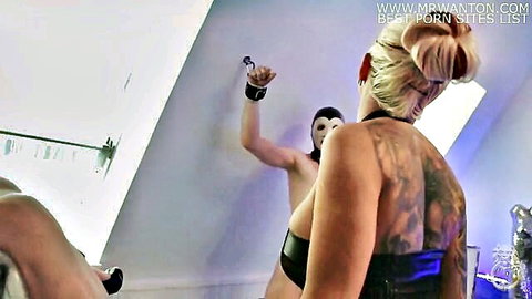 Tattooed blonde in BDSM harness bent over getting fucked doggystyle by masked muscular man