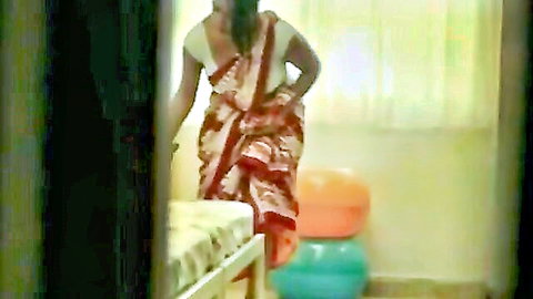 Sexy Indian woman in revealing red saree teasing in bedroom doorway