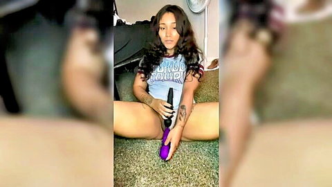 Mixed ethnicity woman in blue tee spreads legs holding purple vibrator crotch tease