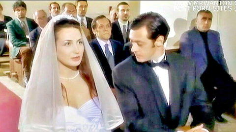 Bride in white wedding dress with veil exchanges vows with groom in tuxedo, hardcore scene