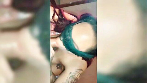 Tattooed woman with green hair and blindfold, exposed breasts in creampie scene