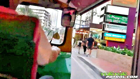 Street view from tuk-tuk in Thailand showing pedestrians walking past shops and green plants