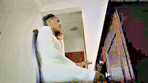 Curvy African woman in tight white dress sits on phone, showcasing booty