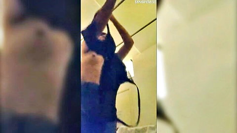 Blurry Asian woman lifting black top, arms raised in erotic pose