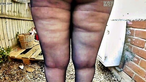 Curvy woman nude in black pantyhose outdoors in yard