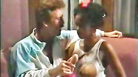 Vintage 1986 interracial scene: white man fondles black woman's exposed breast