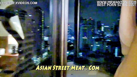 Nighttime city skyline from hotel window with Asian street meat watermark and woman's arm in amateur porn thumbnail