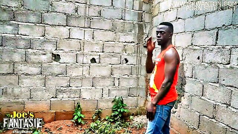 Muscular ebony stud in red tank top and jeans posing against concrete wall for intense black porn action