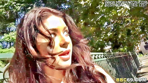 Seductive long-haired brunette with plump glossy lips teasing outdoors near fence for BBC blowbang