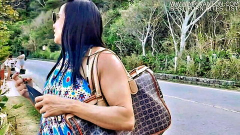 Mature Asian woman in floral blue dress on beach road, seducing surfer fan