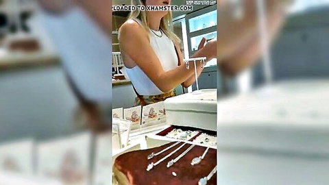 Blonde white woman in tank top handling silver jewelry display