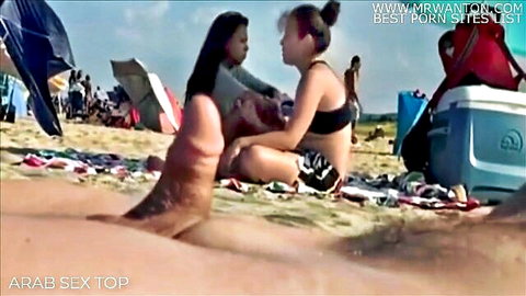 Two bikini girls eyeing erect boner on public beach