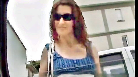 Curly redhead babe in sunglasses showing deep cleavage in skimpy blue top outdoors