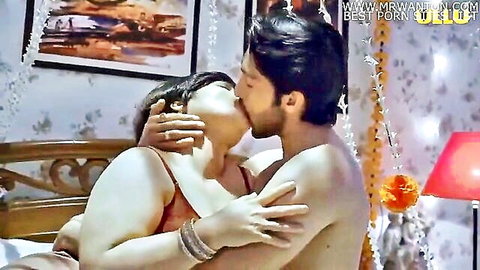 Busty Indian BBW MILF passionately kissing muscular shirtless hunk on bed