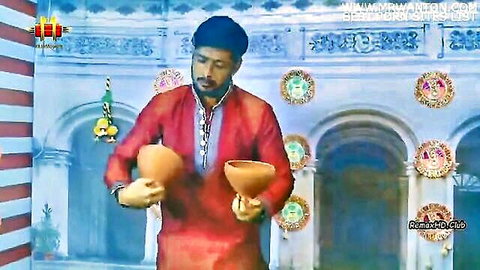 Man in red traditional attire performing Dhunuchi Nach dance with earthen pots