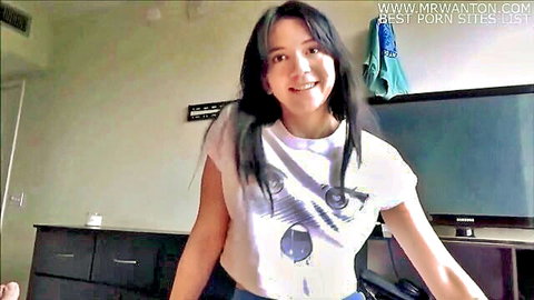 Riley Jean smiling in white graphic tee and blue shorts, step-sister taboo vibe