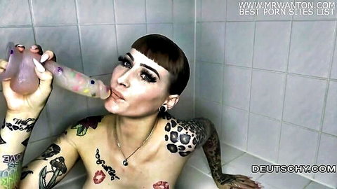 Tattooed German teen sucking pink dildo in solo play