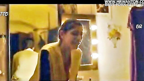 Sexy Indian babe in sheer top smiling teasingly at mirror with man behind in bathroom