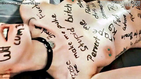 Naked humiliated slut with body writing 'fuck me bitch slut pervert' on tits and body, nipple piercings, BDSM collar