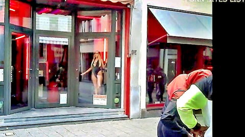 Blonde babe in skimpy black bikini teasing with huge tits from gentlemen's club window as guys watch outside