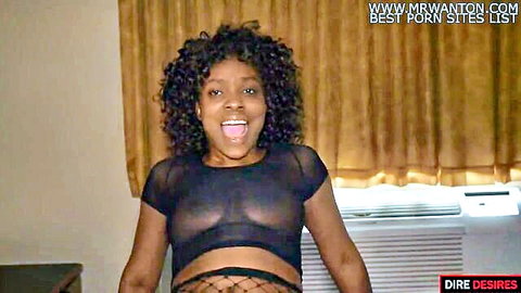 Excited ebony woman smiling wide in sheer black mesh top revealing nipples and fishnet stockings