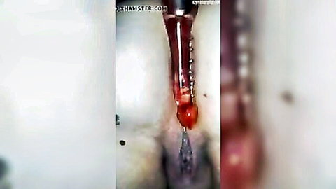 Blurry closeup of woman's stretched anus with red toy inserted and bloody fluid dripping