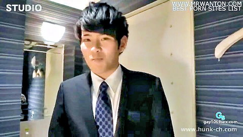 Handsome Asian salaryman in sharp black suit and tie, seductive pose