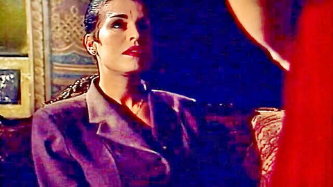 Vintage Italian woman in open purple suit jacket teasing with deep cleavage in luxurious retro bedroom