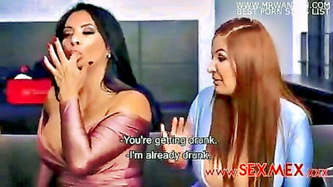 Sexy Latina brunette teases with open mouth gesture while redhead friend grinds playfully behind showing cleavage