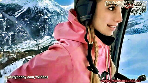 Smiling blonde babe in pink hoodie on snowy ski lift gondola with mountains